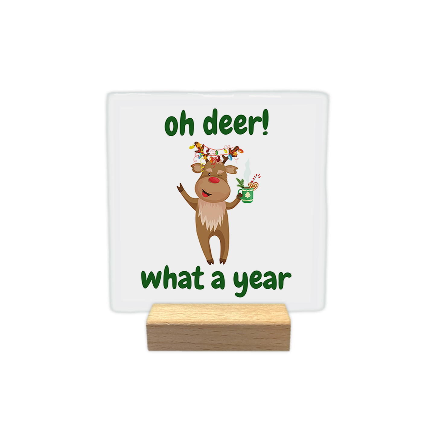 Oh deer! What a year - Decoratie tegel - Formaat: - Op deze decoratie tegel staat een lichte achtergrond met een illustratie van een rendier in het midden. Het rendier heeft kerstverlichting in zijn gewei en houdt een groene mok vast. Boven en onder het rendier staat in groene letters de tekst oh deer! what a year. - Snelwenskaart