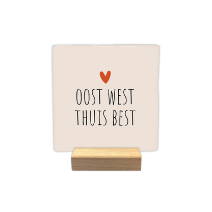 Oost west thuis best - Decoratie tegel - Formaat: - Op deze decoratie tegel staat de tekst "oost west thuis best" in zwarte letters. Boven de tekst is een klein oranje hartje afgebeeld. De achtergrond van de tegel is lichtbeige. - Snelwenskaart