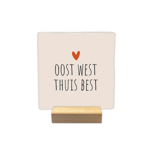 Oost west thuis best - Decoratie tegel - Formaat: - Op deze decoratie tegel staat de tekst "oost west thuis best" in zwarte letters. Boven de tekst is een klein oranje hartje afgebeeld. De achtergrond van de tegel is lichtbeige. - Snelwenskaart