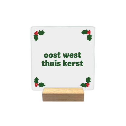 Oost west thuis kerst - Decoratie tegel - Formaat: - Op deze decoratie tegel staat een witte achtergrond met in alle vier de hoeken groene hulstblaadjes en rode bessen. In het midden staat in groene letters de tekst oost west thuis kerst. - Snelwenskaart