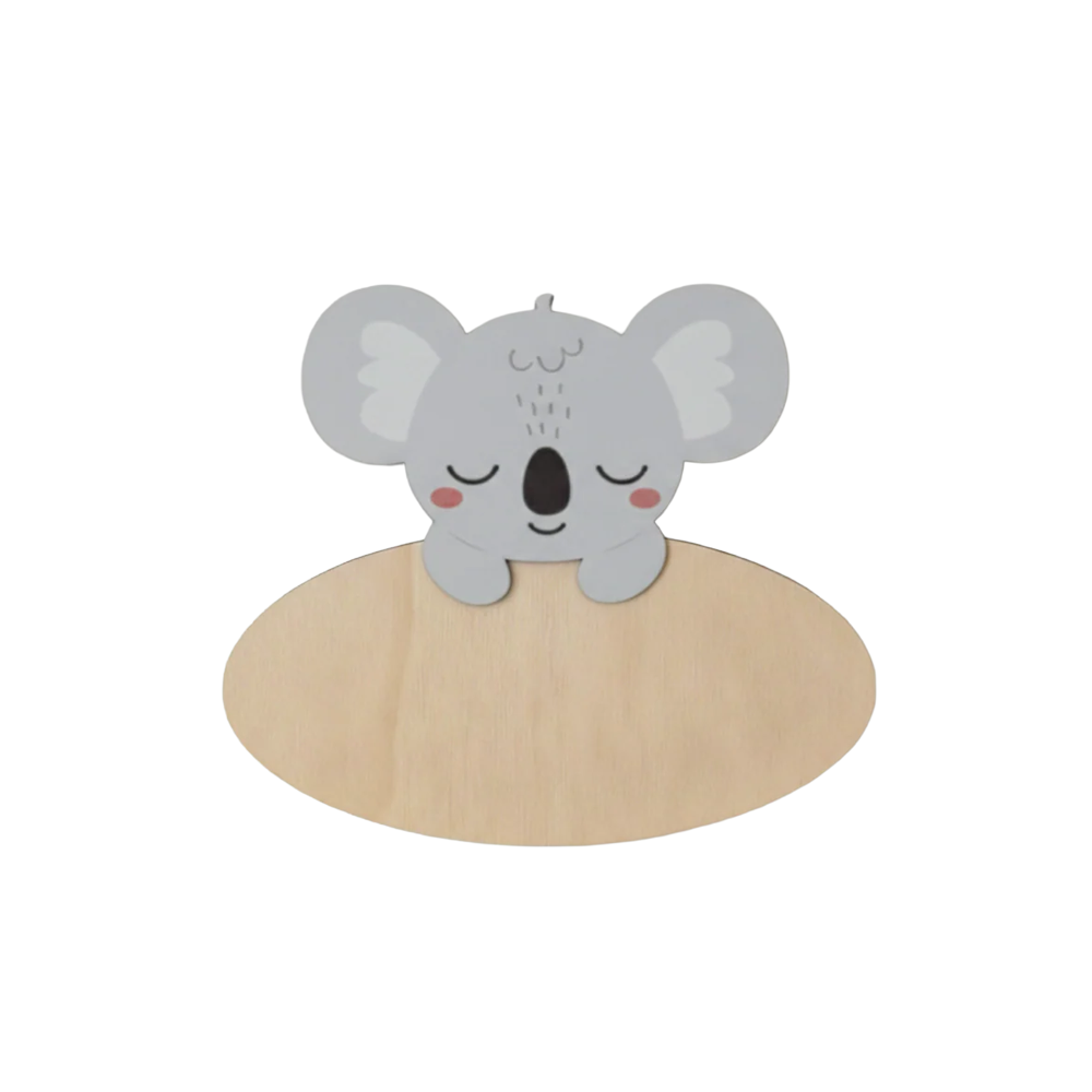 Dit naambord is voorzien van een schattige, slapende koala in grijstinten met grote, ronde oren en rode blosjes op de wangen. De koala steunt met twee pootjes over de bovenkant van een ovaal houten bord heen.