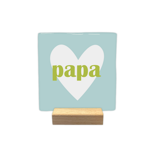Papa - Decoratie tegel - Formaat: - Op deze decoratie tegel staat centraal een groot wit hart afgebeeld tegen een lichtblauwe achtergrond. In het midden van dit hart is het woord "papa" in kleine, groene letters geplaatst. Het ontwerp is eenvoudig en rustig van uitstraling. - Snelwenskaart