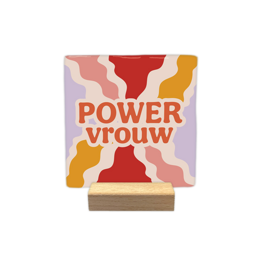 Power vrouw - Decoratie tegel - Formaat: 10 x 10 cm -  Op deze decoratietegel staat in het midden de Nederlandse tekst "POWER vrouw". De tegel zelf is vierkant, staat in een houten standaard en heeft een retro achtergrond met golvende stralen in de kleuren rood, okergeel, roze en lila. De tekst is verdeeld over twee regels en is geschreven in dikke, oranje letters met een brede, beige omlijning. Het woord "POWER" staat volledig in hoofdletters, terwijl "vrouw" in kleine letters is geschreven - Snelwenskaart