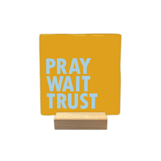 Pray wait trust - Decoratie tegel - Formaat: - Op deze decoratie tegel staat de tekst "pray", "wait" en "trust" onder elkaar in lichtblauwe letters. De woorden zijn links uitgelijnd en uitgevoerd in een strak, vet lettertype. De achtergrond van de tegel is een egale, heldergele kleur. - Snelwenskaart