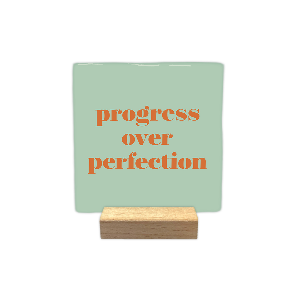 Progress over perfection - Decoratie tegel - Formaat: - Op deze decoratietegel staat de tekst "progress over perfection" in kleine letters met een schreeflettertype. De tekst is uitgevoerd in een oranje kleur en is gecentreerd op een mintgroene achtergrond. - Snelwenskaart