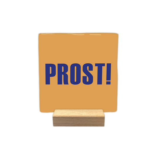 Prost! - Decoratie tegel - Formaat: - Op deze decoratie tegel staat het woord "prost!" afgebeeld in blauwe letters. De achtergrond van de tegel is oranje van kleur. - Snelwenskaart