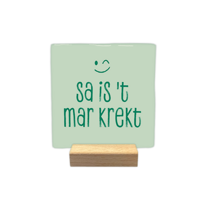 Sa is 't mar krekt - Decoratie tegel - Formaat: - Op deze decoratie tegel staat de tekst "sa is 't mar krekt" in groene letters afgebeeld. Boven de tekst is een groen knipogend gezichtje getekend. De achtergrond van de tegel is lichtgroen van kleur. - Snelwenskaart