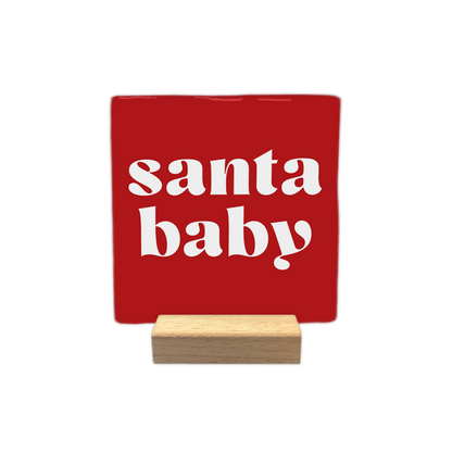 Santa baby - Decoratie tegel - Formaat: - Op deze decoratie tegel staat een rode achtergrond met witte letters. In het midden van de tegel staat de tekst santa baby in twee regels gedrukt. - Snelwenskaart