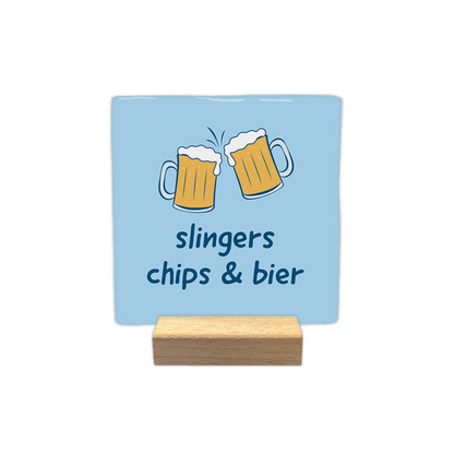 Slingers chips & bier - Decoratie tegel - Formaat: - Op deze decoratie tegel staan twee biertjes. Onder de biertjes staat in donkerblauw de tekst 'Slingers chips & bier'. De achtergrond van de decoratie tegel is licht blauw. - Snelwenskaart