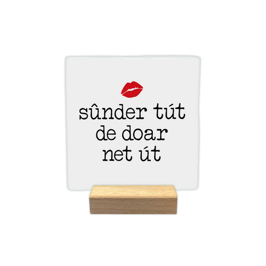 Sûnder tút de doar net út - Decoratie tegel - Formaat: - Op deze decoratie tegel staat de tekst "sûnder tút de doar net út" in zwarte letters centraal afgebeeld, zoals te zien is in RTK456.jpg. Boven de tekst bevindt zich een afbeelding van rode lippen. De achtergrond van de tegel is wit. - Snelwenskaart