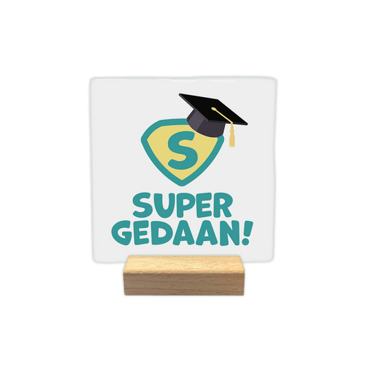 Super gedaan! - Decoratie tegel - Formaat: - Op deze decoratie tegel staat een geel en groen superman logo met een afstudeerhoed erop. Onder het logo staat in het groen de tekst 'Super gedaan!'. - Snelwenskaart