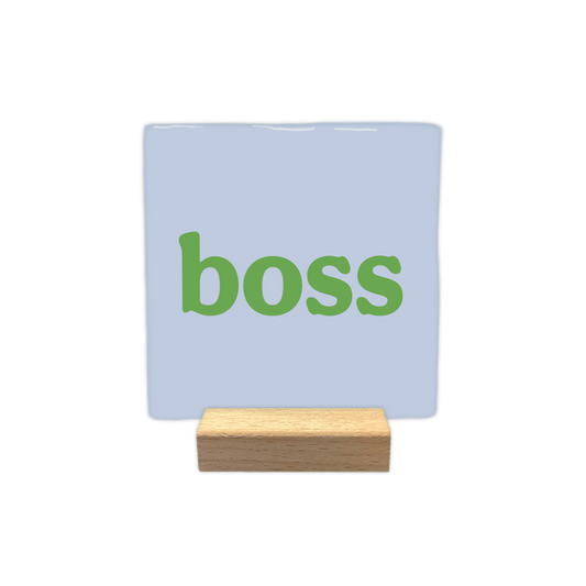 Decoratietegel – 10 x 10 cm - Op deze decoratietegel staat in het midden in groene letters het woord "boss". De achtergrond van de vierkante tegel is effen lichtblauw.