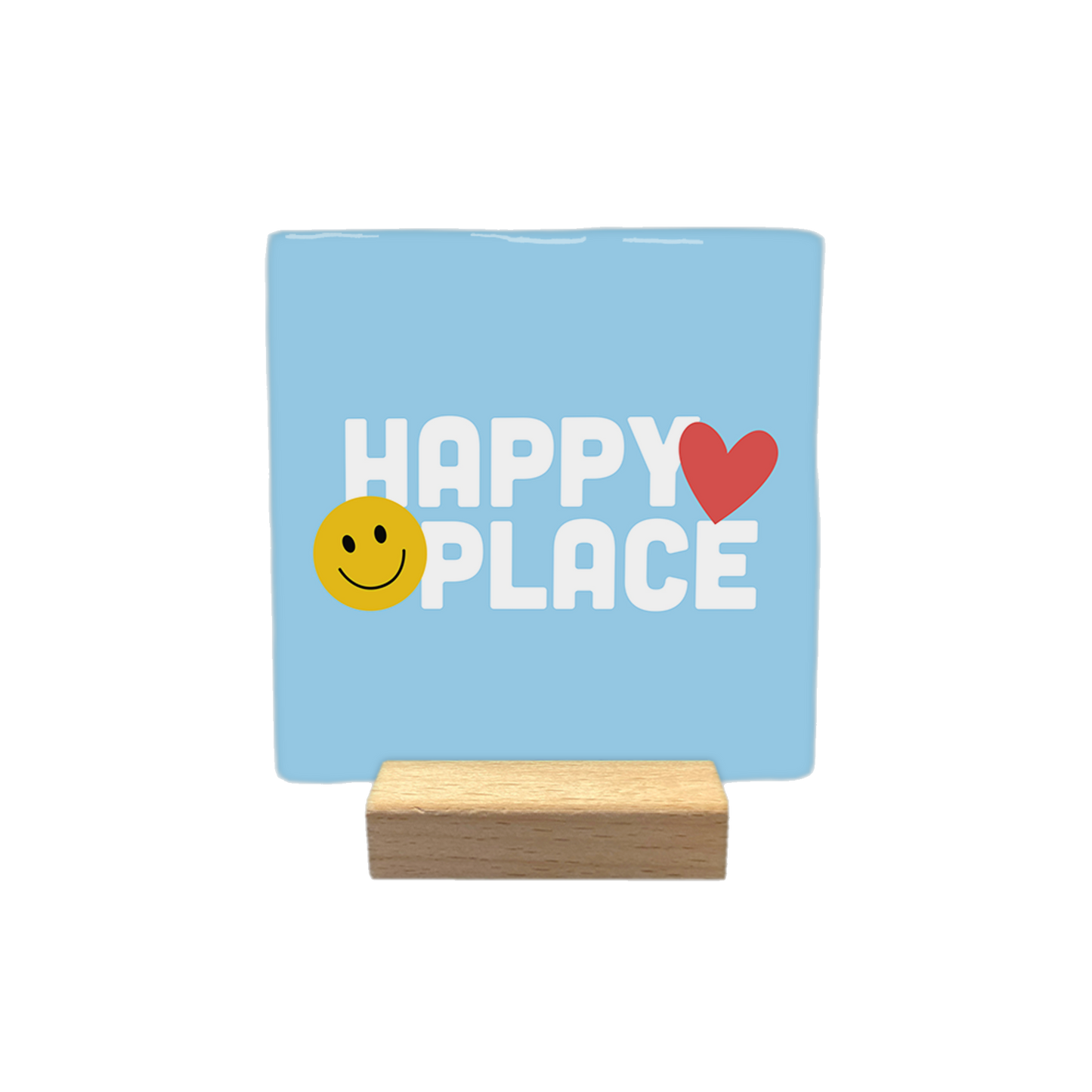 Decoratietegel – 10 x 10 cm - Op deze decoratietegel staat in het midden de tekst "HAPPY PLACE" in witte hoofdletters met een afgerond lettertype. Aan de linkerzijde van het woord "HAPPY" is een geel smiley-icoontje geplaatst, terwijl aan de rechterzijde van het woord "HAPPY" een rood hartje staat. Het ontwerp is gecentreerd op een lichtblauwe achtergrond.