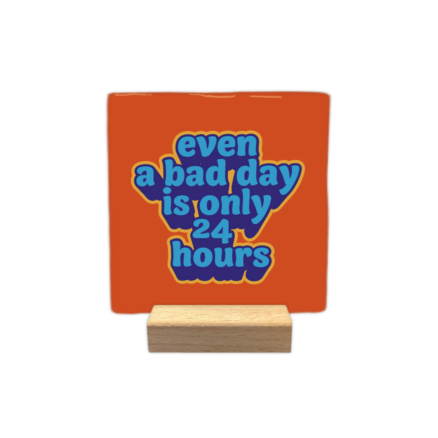 Op deze wenskaart staat een oranje, vierkante tegel in een houten standaard. In het midden staat de Engelse tekst "even a bad day is only 24 hours". De letters zijn dik en blauw, met een gele rand die voor een 3D-effect zorgt.