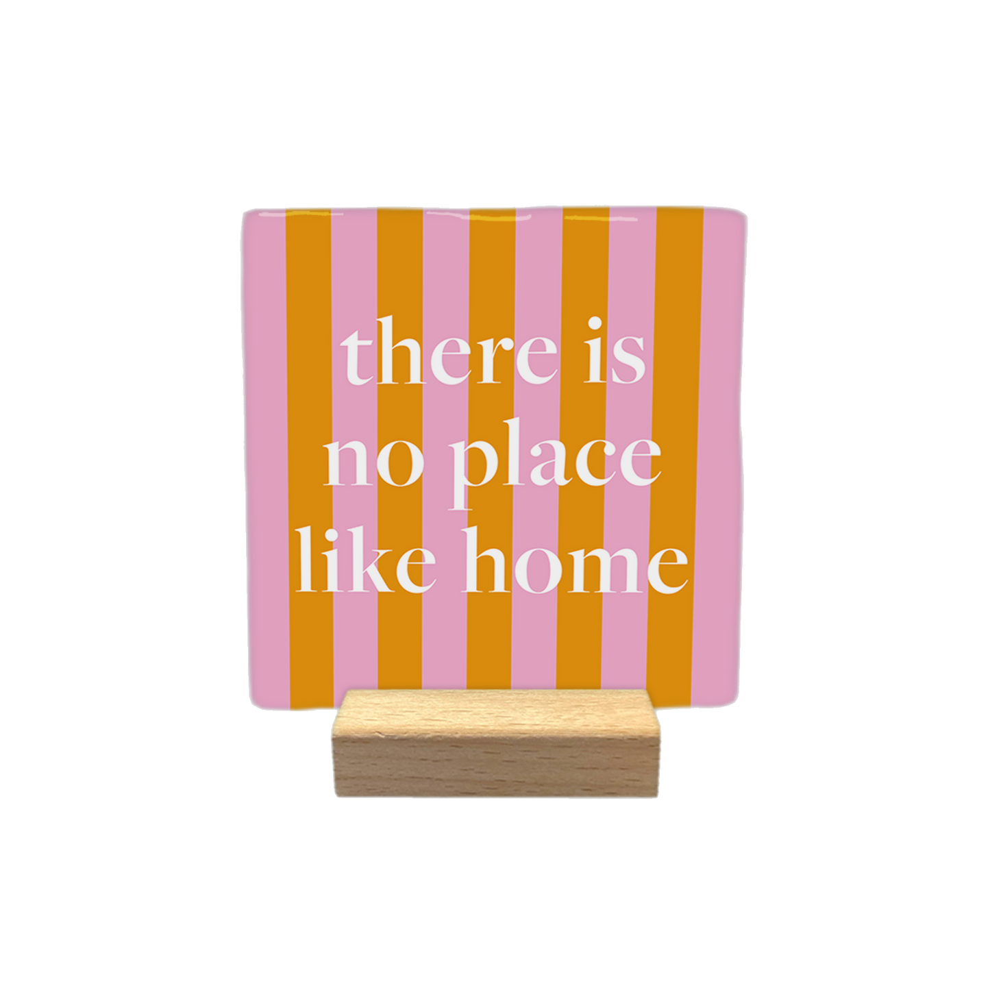 Decoratietegel – 10 x 10 cm - Op deze decoratietegel staat de tekst "there is no place like home" in witte letters met een klassiek schreeflettertype. De tekst is gecentreerd op een vierkante achtergrond met verticale roze en oranje strepen. 