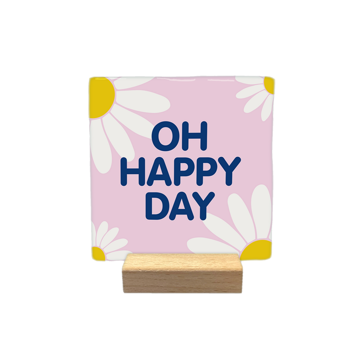 Decoratietegel – 10 x 10 cm - Op deze decoratietegel staat de tekst "OH HAPPY DAY" in donkerblauwe hoofdletters. De tekst is gecentreerd op een lichtroze, vierkante achtergrond die is versierd met gestileerde witte madeliefjes met gele harten in de hoeken.