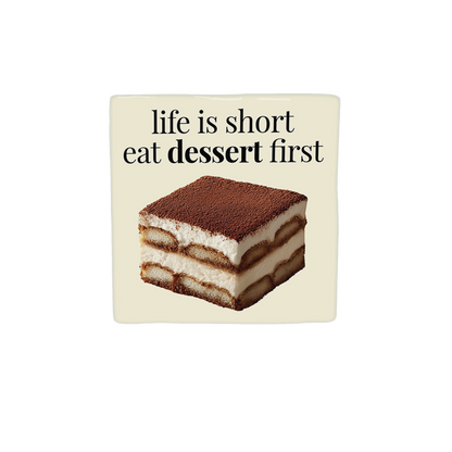 Decoratietegel – 10 x 10 cm - Op deze decoratietegel staat de tekst "life is short eat dessert first" in zwarte letters met een schreeflettertype. Daaronder is een realistische afbeelding van een vierkant stuk tiramisu geplaatst. Het ontwerp is gecentreerd op een crèmekleurige achtergrond. 