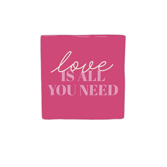 Decoratietegel – 10 x 10 cm - Op deze decoratietegel staat de tekst "love IS ALL YOU NEED" in een combinatie van sierlijke letters voor het woord "love" en strakke hoofdletters voor de rest. De tekst is in lichtroze uitgevoerd en gecentraliseerd op een donkerroze achtergrond. 