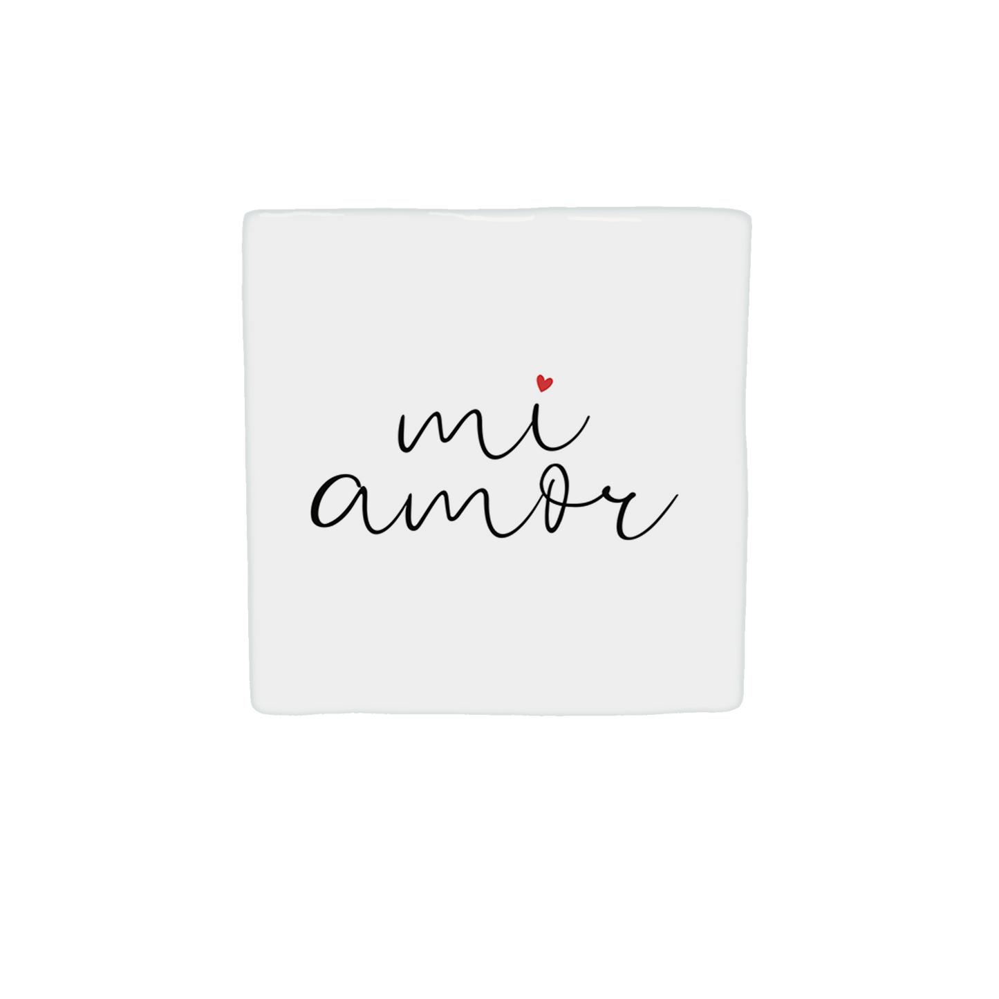  Op deze decoratietegel staat de tekst "mi amor" in een zwart, cursief handschrift. Boven de letter "i" staat een klein, rood hartje. De tekst is gecentreerd op een witte achtergrond. Iedere tegel wordt geleverd inclusief houten presentatieblok. 