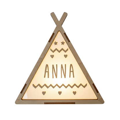Op deze lamp staat een houten tipi-tent afgebeeld met een warme, oplichtende driehoekige voorzijde. Bovenin de lamp zijn twee sterretjes en twee kleine hartjes te zien, met daaronder een naam in houten letters. Onder de naam bevindt zich een zigzaggend patroon en drie kleine hartjes.