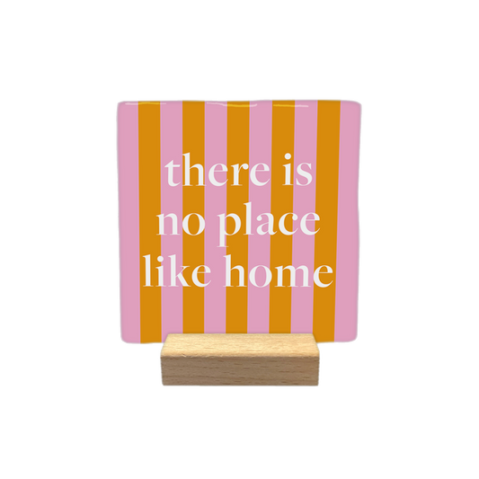 There is no place like home - Decoratie tegel - Formaat: - Op deze decoratietegel staat de tekst "there is no place like home" in witte letters met een klassiek schreeflettertype. De tekst is gecentreerd op een vierkante achtergrond met verticale roze en oranje strepen. - Snelwenskaart