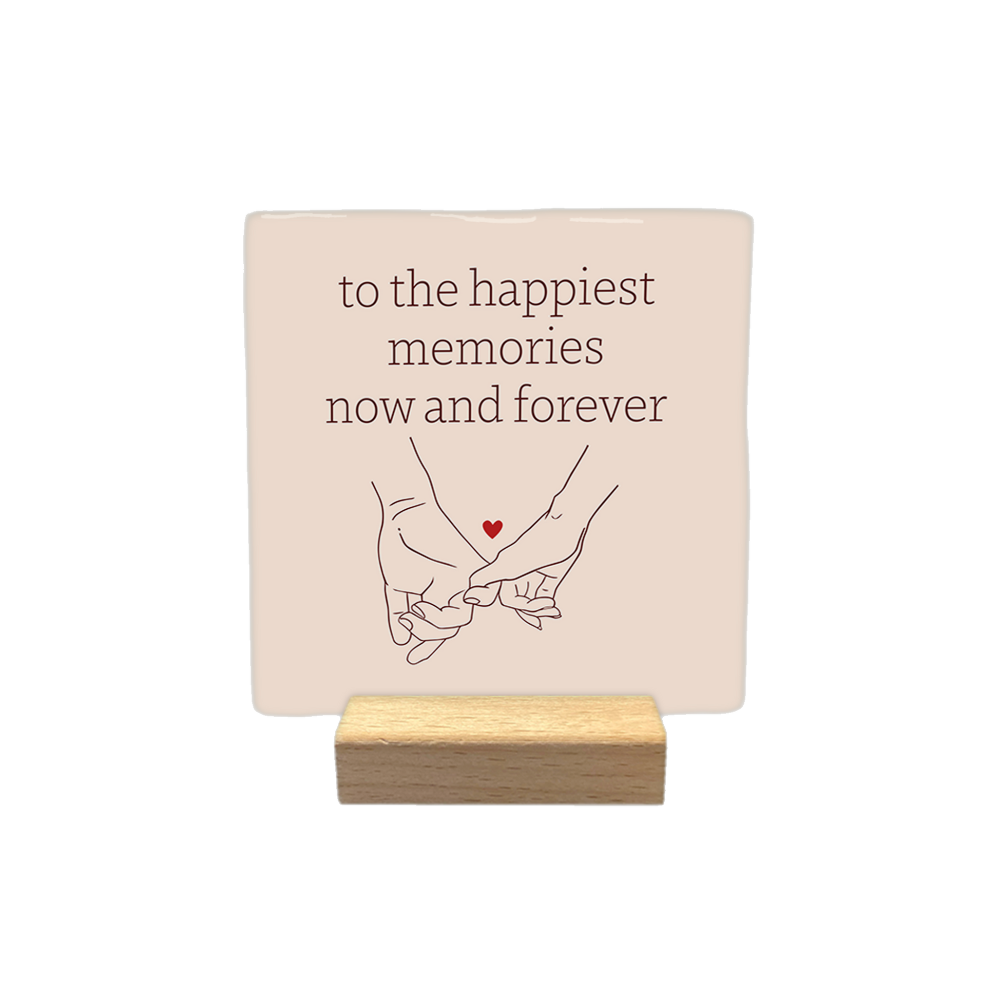 To the happiest memories now and forever - Decoratie tegel - Formaat: - Op deze decoratietegel staat de tekst "to the happiest memories now and forever" in bruine letters, gecentreerd boven een lijntekening van twee handen die elkaars pink vasthouden. Tussen de handen is een klein, rood hartje afgebeeld. Het ontwerp staat op een lichtbeige achtergrond. - Snelwenskaart