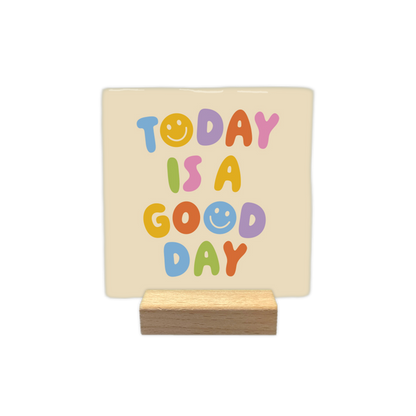 Today is a good day - Decoratie tegel - Formaat: - Op deze decoratietegel staat de tekst "TODAY IS A GOOD DAY" in kleurrijke, speelse letters afgebeeld tegen een crèmekleurige achtergrond. De tekst is opgebouwd uit verschillende pastelkleuren, waarbij de letter "O" in zowel "TODAY" als "GOOD" is vormgegeven als een smiley. Het ontwerp heeft een vrolijke uitstraling door het gebruik van variërende kleuren zoals blauw, geel, paars, oranje, roze en groen. - Snelwenskaart