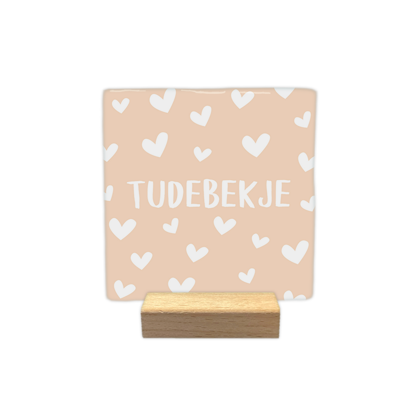 Tudebekje - Decoratie tegel - Formaat: - Op deze decoratie tegel staat de tekst "tudebekje" in witte letters centraal afgebeeld. De achtergrond van de tegel is lichtbeige van kleur en is versierd met een patroon van kleine witte hartjes. - Snelwenskaart