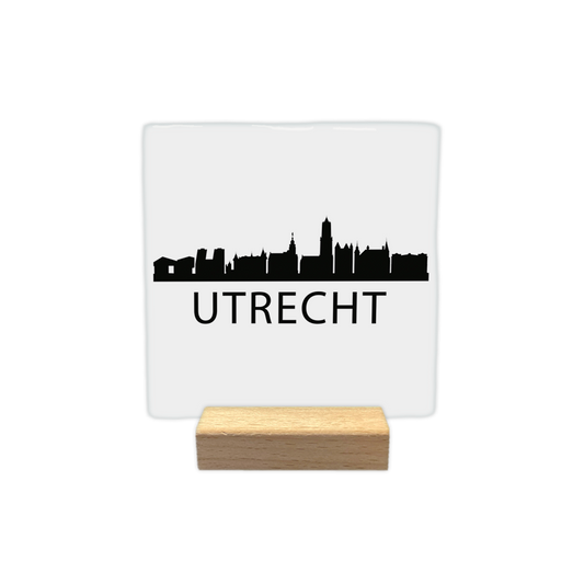 Utrecht skyline - Decoratie tegel - Formaat: - Op deze decoratie tegel staat een zwarte skyline van Utrecht afgebeeld tegen een witte achtergrond. Het silhouet bevat diverse herkenbare gebouwen uit de stad, waaronder de Domtoren. Onder de skyline staat in zwarte letters de plaatsnaam Utrecht. Het ontwerp is minimalistisch uitgevoerd in zwart en wit. - Snelwenskaart