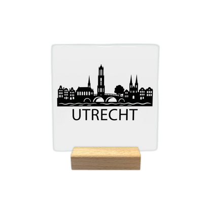 Utrecht skyline - Decoratie tegel - Formaat: - Op deze decoratie tegel staat een zwarte skyline van Utrecht afgebeeld tegen een witte achtergrond. Het silhouet bevat een brug over het water, de Domtoren en historische panden. Onder de skyline staat in zwarte letters de plaatsnaam Utrecht. Het ontwerp is minimalistisch uitgevoerd in zwart en wit. - Snelwenskaart