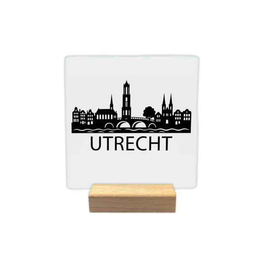 Utrecht skyline - Decoratie tegel - Formaat: - Op deze decoratie tegel staat een zwarte skyline van Utrecht afgebeeld tegen een witte achtergrond. Het silhouet bevat een brug over het water, de Domtoren en historische panden. Onder de skyline staat in zwarte letters de plaatsnaam Utrecht. Het ontwerp is minimalistisch uitgevoerd in zwart en wit. - Snelwenskaart
