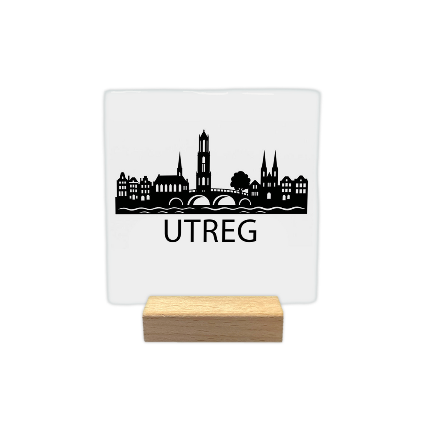 Utreg skyline - Decoratie tegel - Formaat: - Op deze decoratie tegel staat een zwarte skyline van Utrecht afgebeeld tegen een witte achtergrond. Het silhouet bevat een brug over het water, de Domtoren en historische panden. Onder de skyline staat in zwarte letters de tekst "Utreg". Het ontwerp is minimalistisch uitgevoerd in zwart en wit. - Snelwenskaart