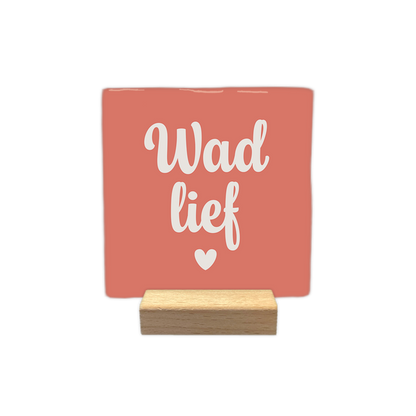 Wad lief - Decoratie tegel - Formaat: - Op deze decoratie tegel staat de tekst "Wad lief" in crèmekleurige, sierlijke letters centraal afgebeeld. Onder de tekst bevindt zich een klein, crèmekleurig hartje. De achtergrond van de tegel is koraalkleurig. - Snelwenskaart