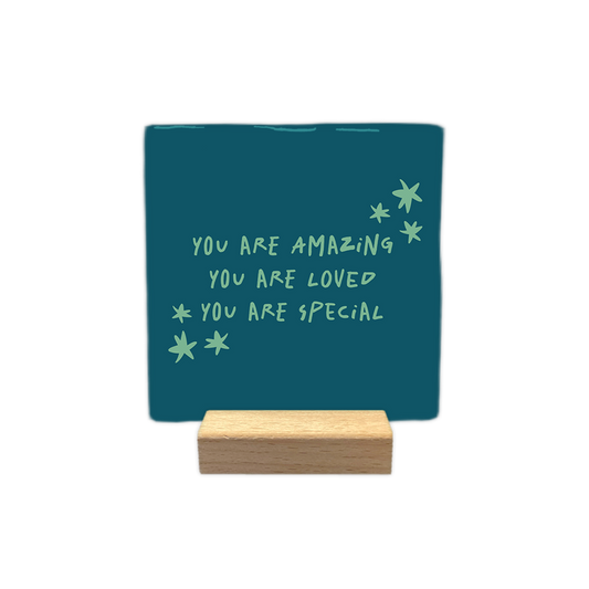 You are amazing - Decoratie tegel - Formaat: - Op deze decoratie tegel staat de tekst "you are amazing, you are loved, you are special" in lichtgroene, handgeschreven letters. Om de tekst heen zijn enkele kleine, eveneens lichtgroene sterretjes afgebeeld. Het ontwerp is geplaatst tegen een donkerblauwe achtergrond. - Snelwenskaart