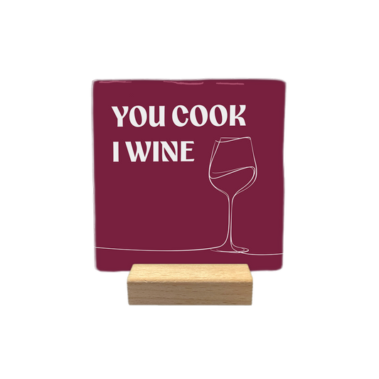 You cook I wine - Decoratie tegel - Formaat: - Op deze decoratietegel staat de tekst "YOU COOK I WINE" in witte hoofdletters. Aan de rechterkant is een minimalistische lijntekening van een wijnglas afgebeeld. De tekst en de tekening staan op een dieprode achtergrond. - Snelwenskaart