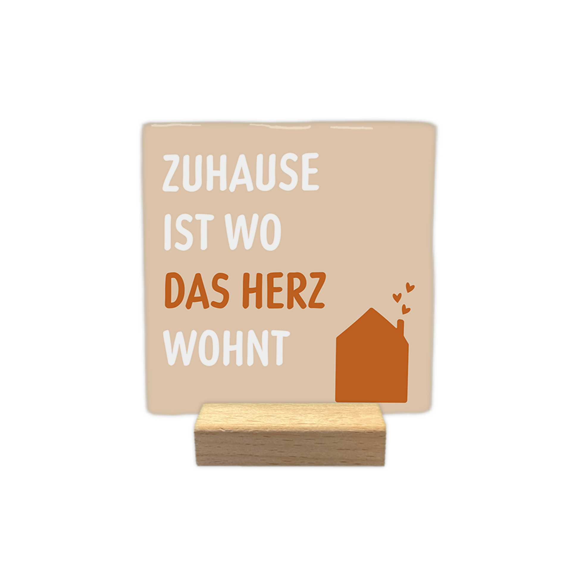 Zuhause ist wo das herz wohnt - Decoratie tegel - Formaat: - Op deze decoratie tegel staat de tekst "zuhause ist wo das herz wohnt" afgebeeld. De tekst is verdeeld over vier regels, waarbij de woorden "zuhause", "ist" en "wohnt" in het wit zijn geschreven en het woord "herz" in het bruin. Rechtsonder staat een bruine illustratie van een huis met drie kleine hartjes die uit de schoorsteen stijgen. De achtergrond van het ontwerp is lichtbeige. - Snelwenskaart