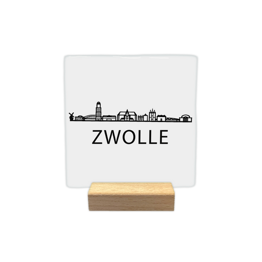 Zwolle skyline - Decoratie tegel - Formaat: - Op deze decoratie tegel staat een zwarte skyline van Zwolle afgebeeld tegen een witte achtergrond. In het silhouet zijn verschillende herkenbare gebouwen uit de stad verwerkt, waaronder een molen en diverse torens. Onder de skyline staat in zwarte letters de plaatsnaam Zwolle. Het ontwerp is uitgevoerd in een minimalistische zwart-witstijl. - Snelwenskaart