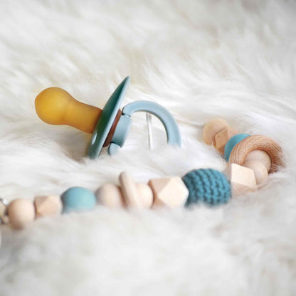 Op deze wenskaart staat een foto van een blauwe babyspeen. 