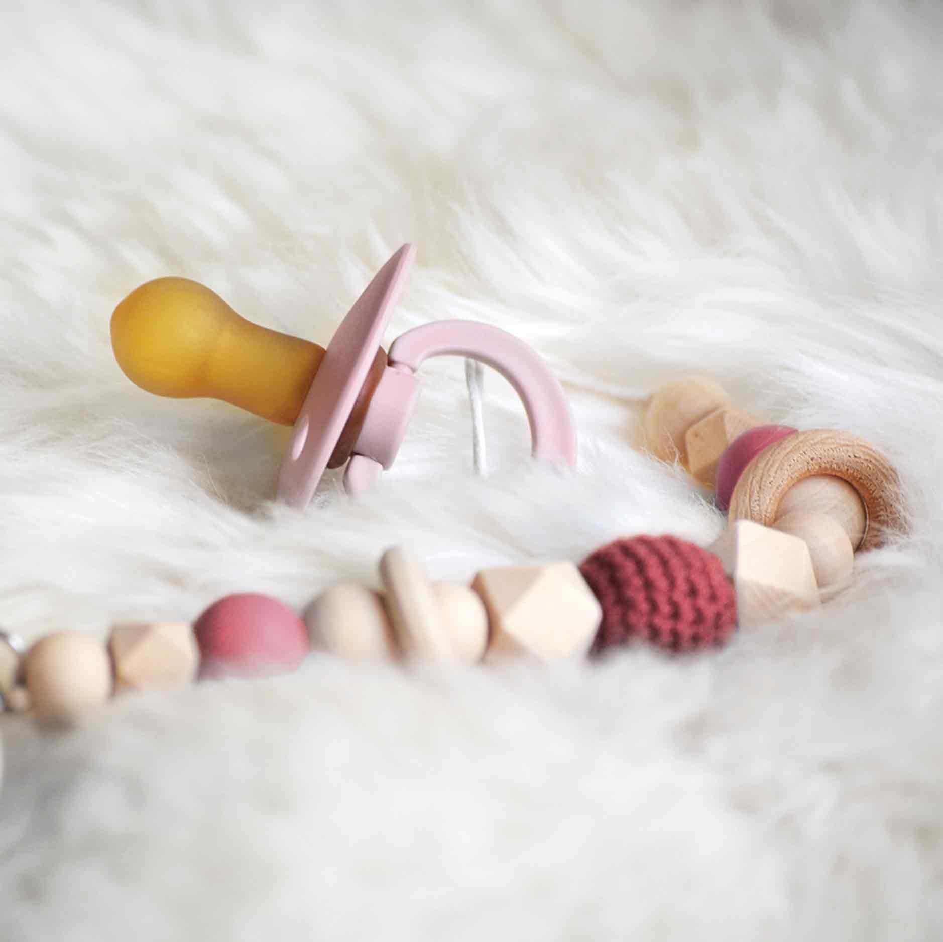 Op deze wenskaart staat een foto van een roze babyspeen. 