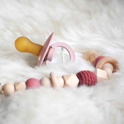 Op deze wenskaart staat een foto van een roze babyspeen. 