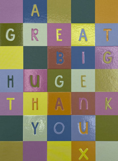 Op deze wenskaart staan vakjes in de kleuren paars, groen, oranje, geel, rood en blauw. In de vakjes staan letters die de tekst: "A great big hug thank you x" vormen. 