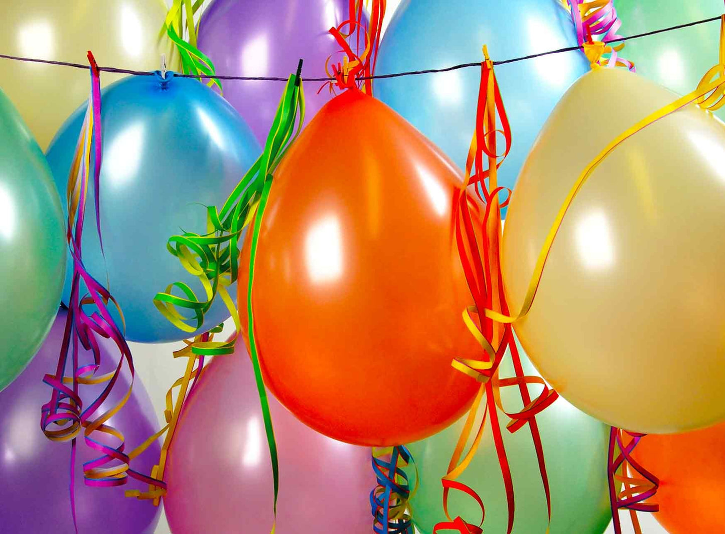 Op deze wenskaart staan ballonnen in de kleuren blauw, paars, oranje, geel, groen en roze. 