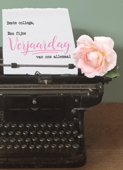 Op deze wenskaart staat een zwarte typmachine waar een blaadje zit met de tekst: "Beste collega, een fijne verjaardag van ons allemaal".